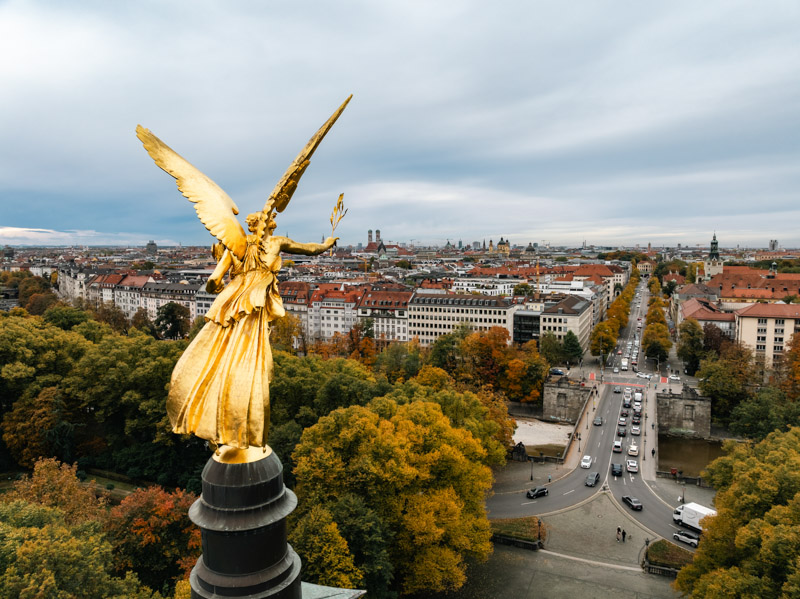 Stadtansicht des goldenen Friedensengels in München mit Blick über die Prinzregentenstraße zur Frauenkirche im Herbst, fotografiert von Max Sydow