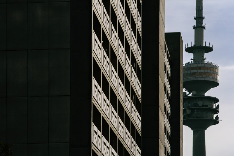Stadtansicht des Olympiaturms in München hinter moderner Hochhausarchitektur, fotografiert von Max Sydow